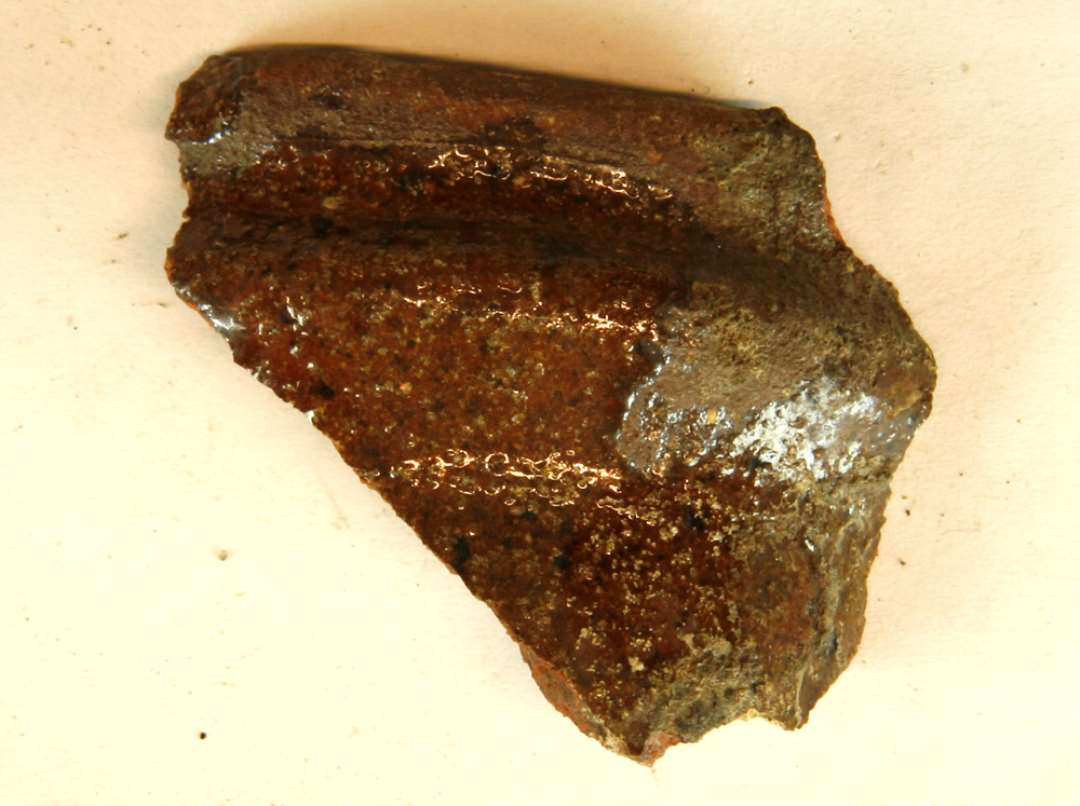 1 mundingsrandskår af kande af rødbrændt lergods med klar blyglasur på ydersiden, gruppe 1.