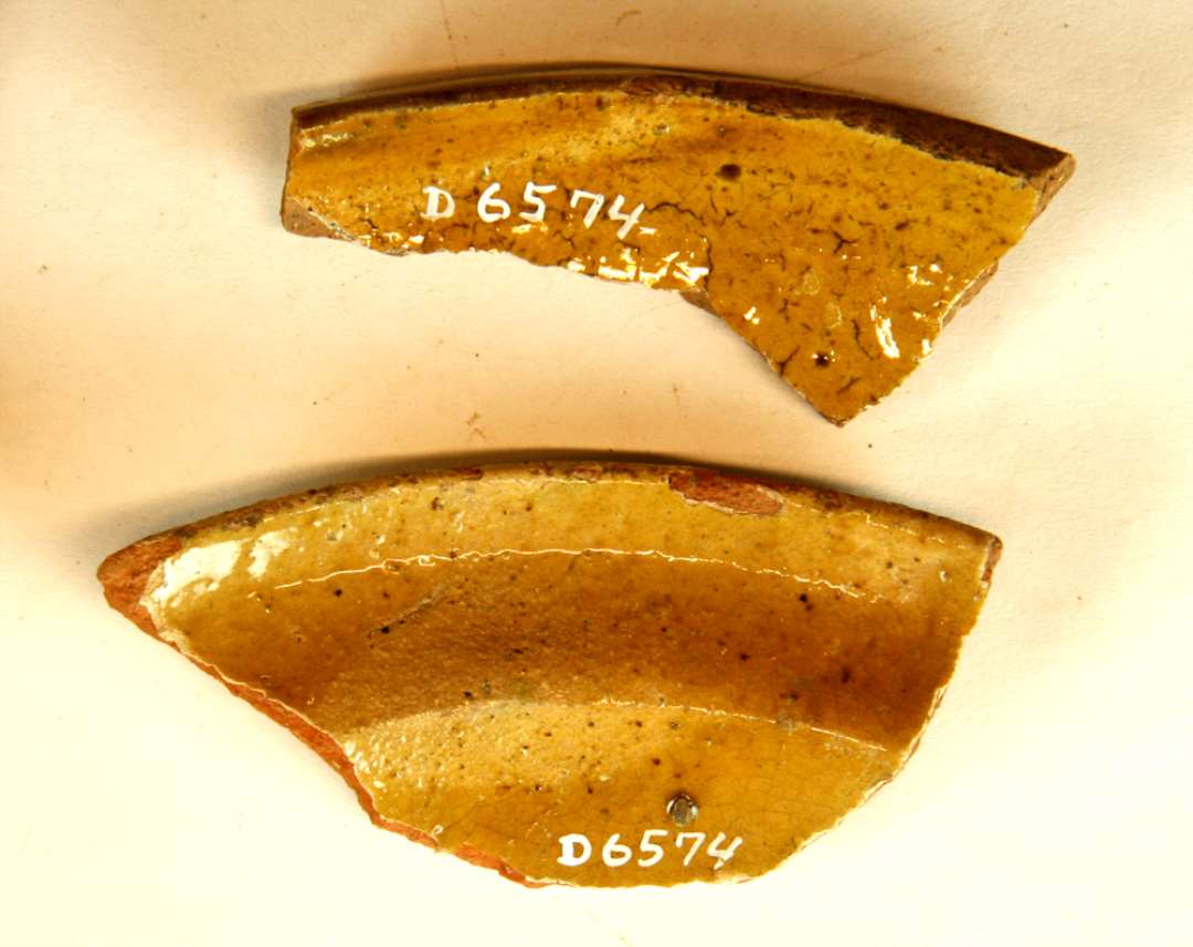 2 mundingsrandskår fra skåle af rødbrændt lergods med pibelersbegitning og klar blyglasur på indersiden, gruppe 1.  