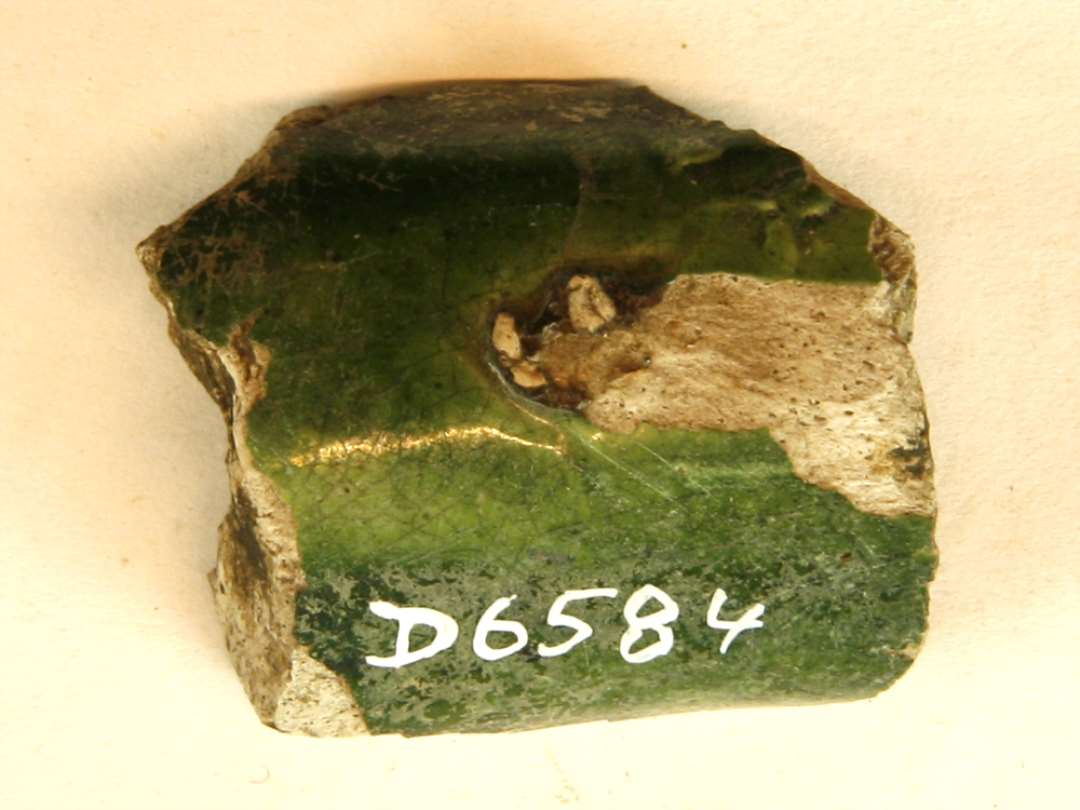 1 fragment af tud ( ? ) af gråligt, porøst pibelersagtigt gods med grøn blyglasur på ydersiden.
