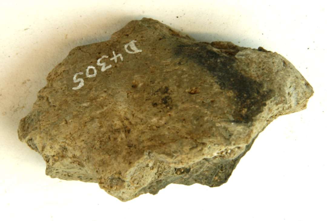1 fragment af discosformet vævevægt af gråbrunlig brændt lermasse. Største mål: 7 cm.