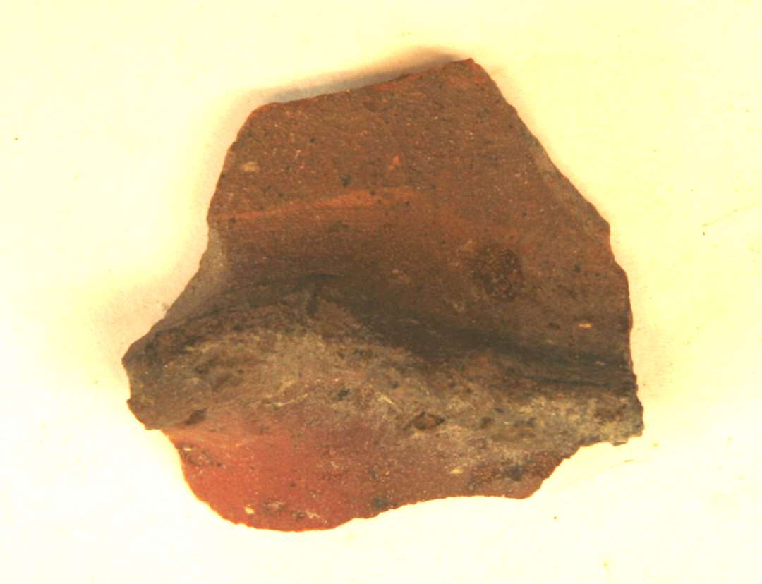 1 fodrandskår fra kande af rødbrændt lergods med fremtrædende, bølgende fodrand. På ydersiden ses pletter af klar blyglasur, gruppe 1.