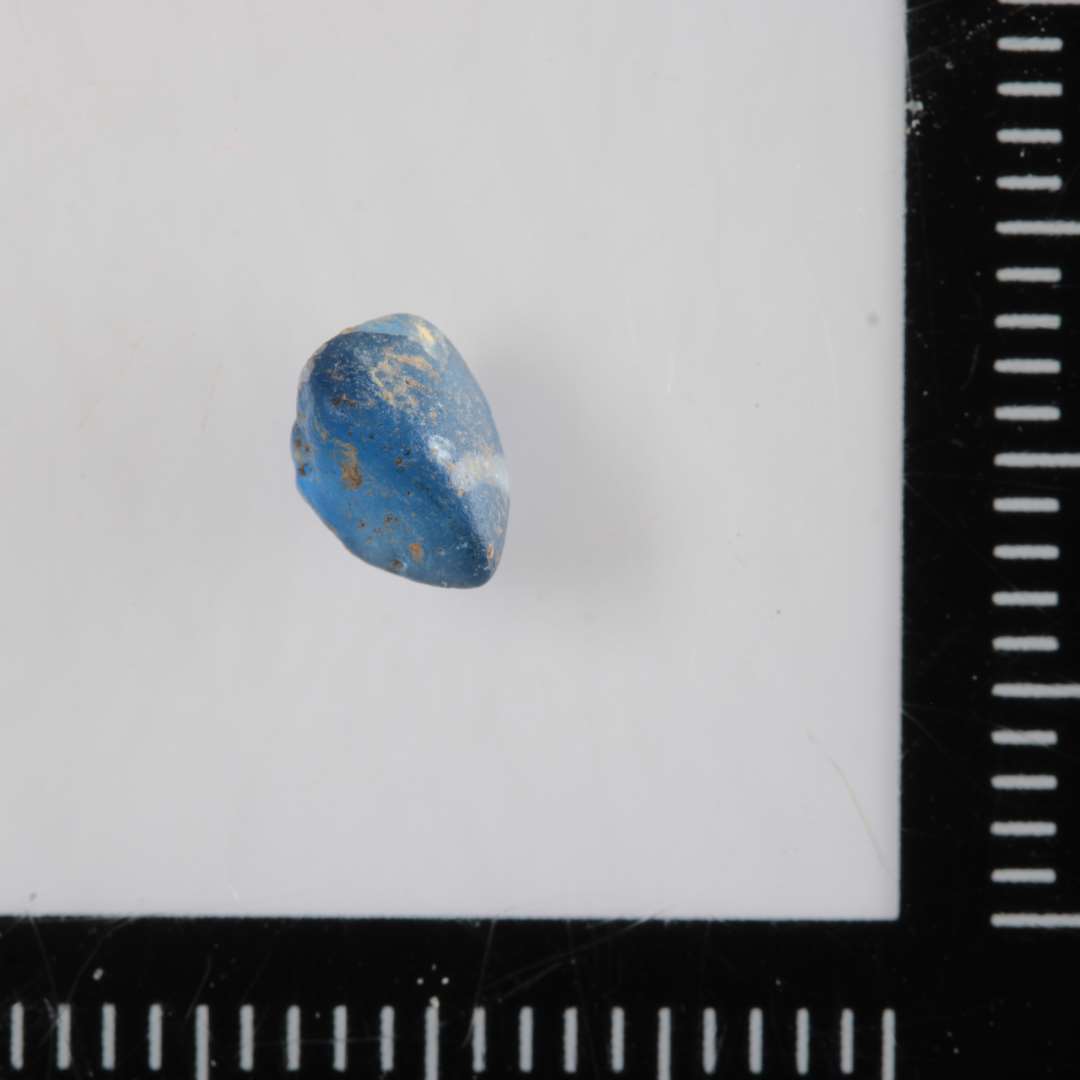 1 fragment af perle af blåligt, gennemsigtigt glas med spor af indsmeltet hvid glastråd.