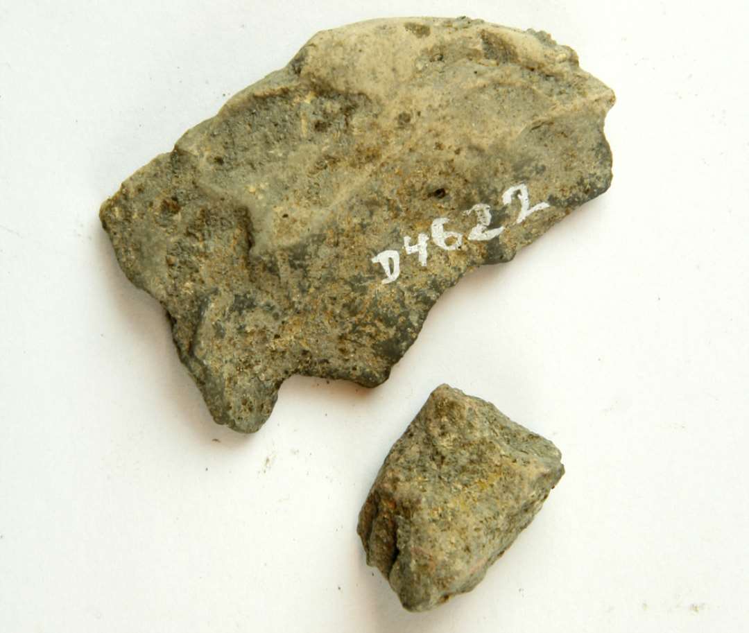 2 fragmenter af vævevægte af gråbrunlig lermasse. Største mål: 2,5-5,5 cm.
