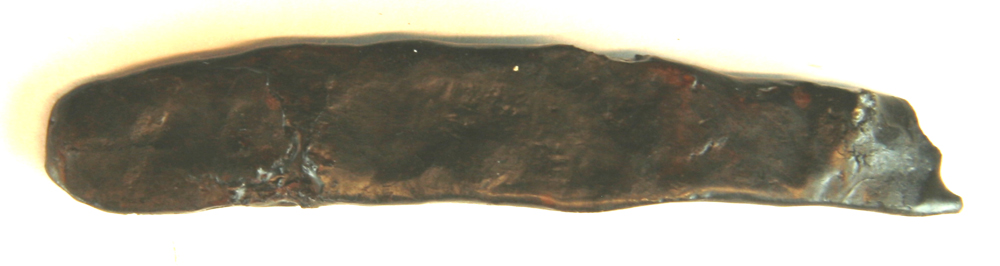 1 forrustet jernstykke af lang, flad, let krummet form afbrudt i den ene ende. L : 7 cm. St. br. 1,3 cm.
