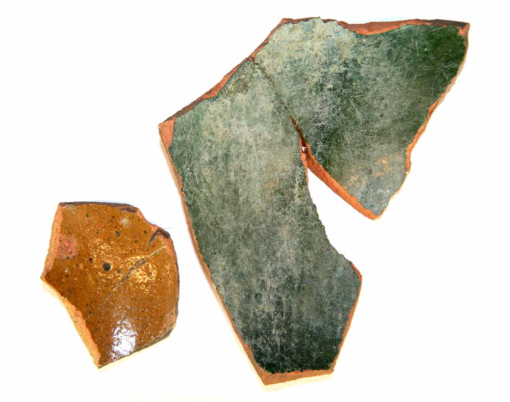 2 side-bundskår fra fade af rødbrændt lergods, det ene med klar, det andet med grøn blyglasur på indersiden.