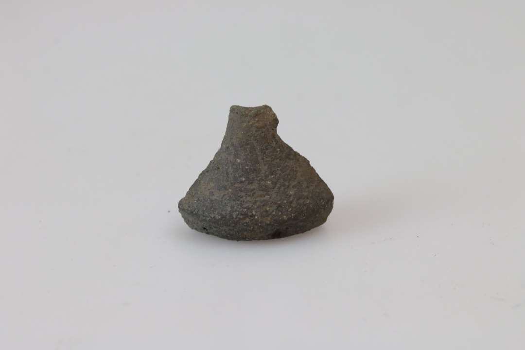 Fragment af tenvægt af brungrålig brændt lermasse og af dobbeltkonisk form.