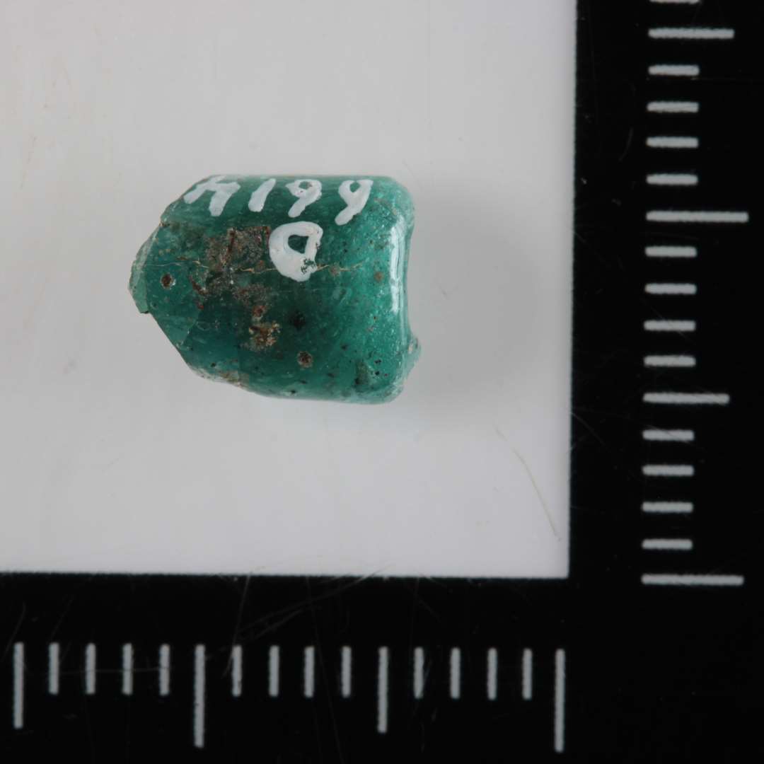 Fragment af cylinderformet perle af delvis gennemsigtigt blågrønligt glas.