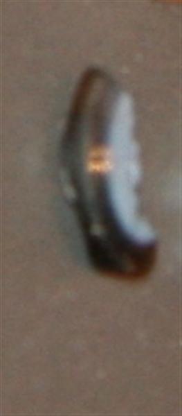 Fragment af romersk gemme af delvist gennemsigtig, brunlig smykkesten med gråblålig overflade. Stenen har flad, antagelig oval form med tilsleben kant og affasning af kanten mod den side, der udviser spor af indgraveret ornament. Længde : 1,2 cm. Br: 0,5 cm. Tyk: 0,3 cm.