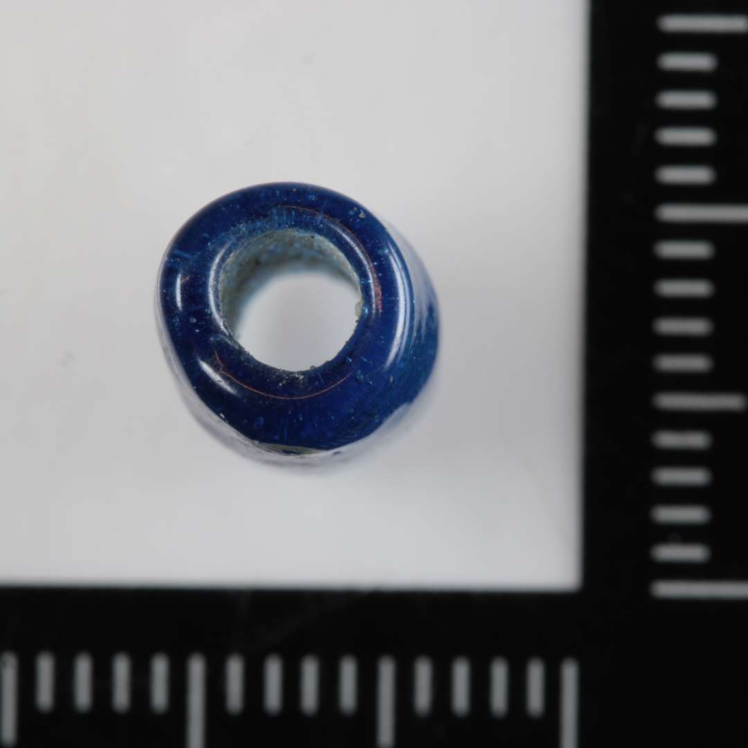 1 aflang cylinderformet perle af gennemsigtigt blåligt glas. 