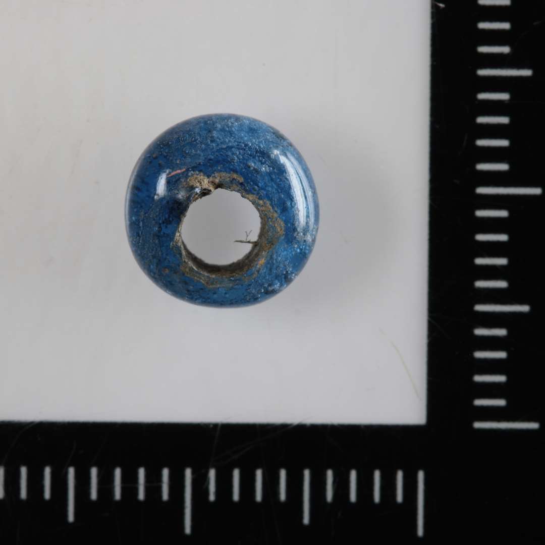 Perle af afrundet ringform og af gennemsigtigt blåligt glas.
