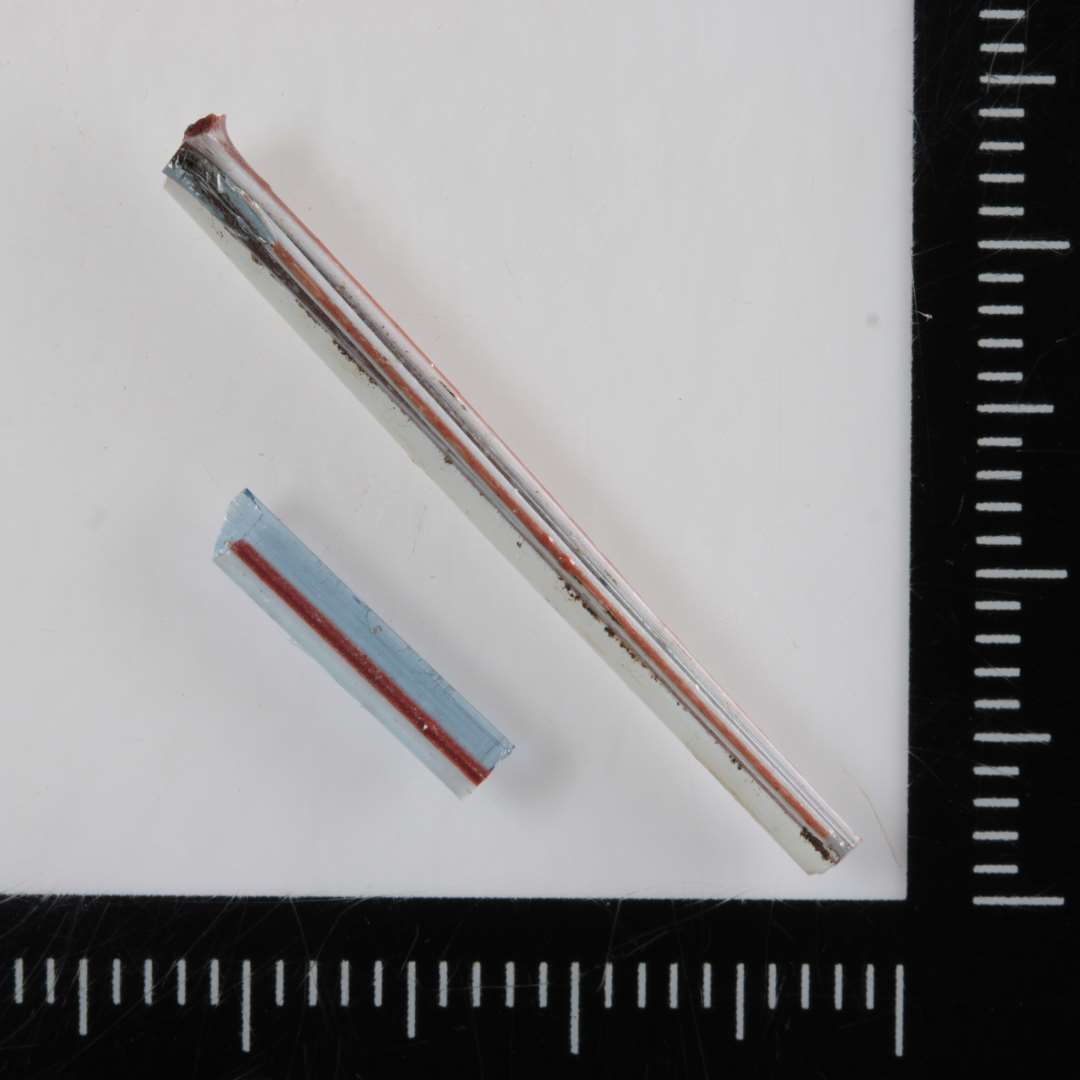 To stumper glastråd dannet af sammensmeltede tyndere tråde af gennemsigtigt svagt blåligt glas og uigennemsigtigt hvidt og rødbrunt glas.