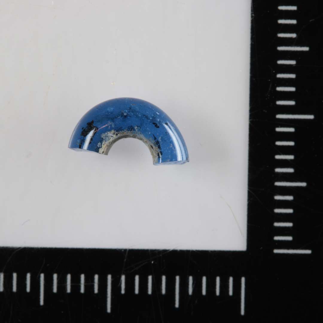 1/2 perle af afrundet ringform og af blåligt gennemsigtigt glas.