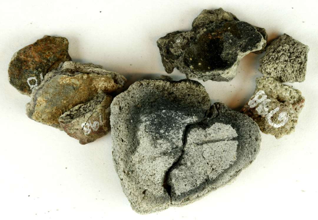 11 fragmenter fra smeltedigler af grålig, finmagret porøst lergods flere med glasuragtig sintringsskorpe på yder- og indersiden. 