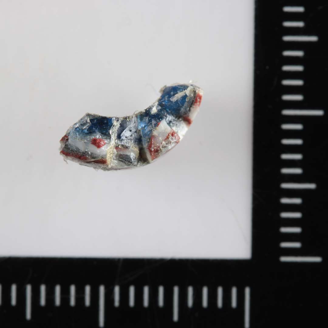 1/3 af cylinderformet perle af gennemsigtigt blåligt glas, hvis yderside er påsmeltet et lag af uregelmæssig rød- og hvidstribet, uigennemsigtig glasmasse. 10 mm. 