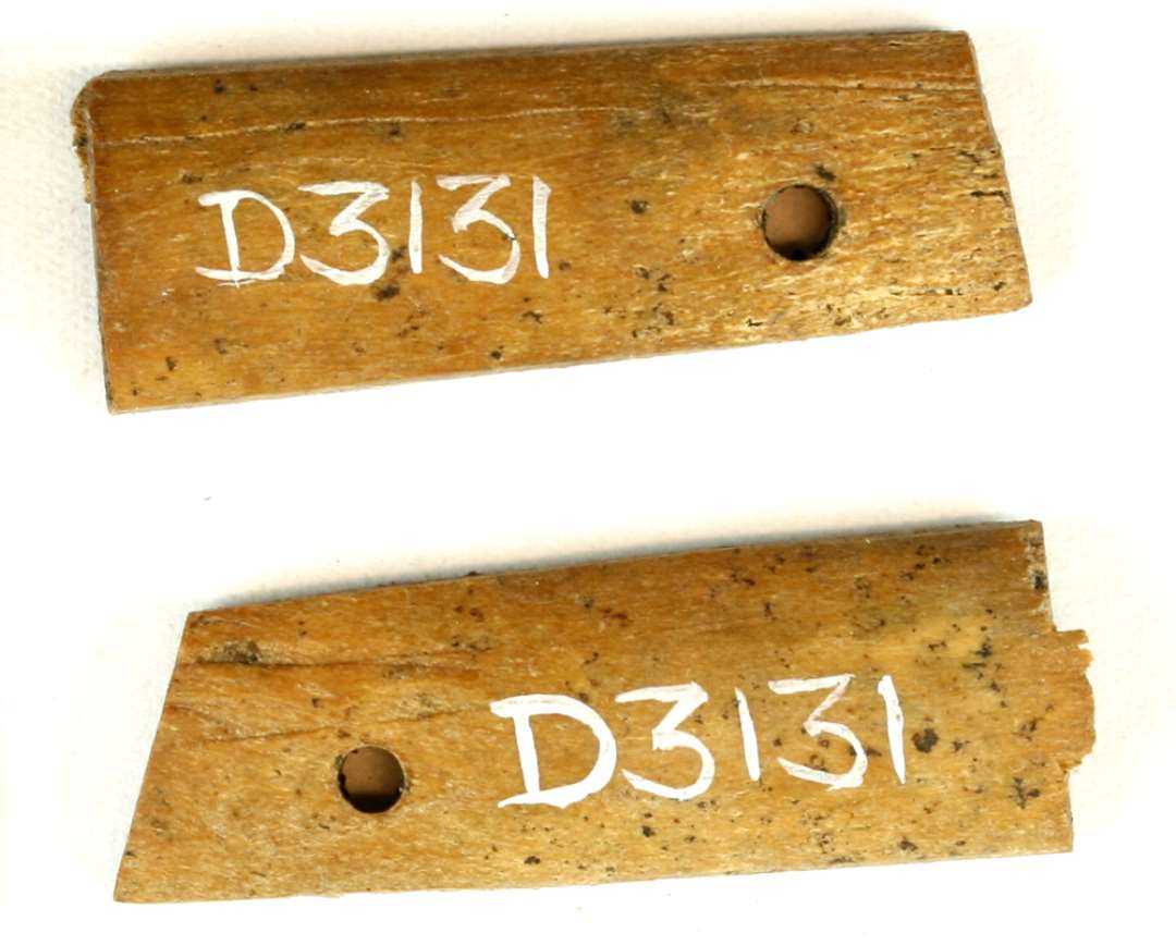 2 stk. af kamskinner, begge lige oversavet i den ene ende og på skrå i den modsatte, hvor stykkerne udviser et naglehul. 