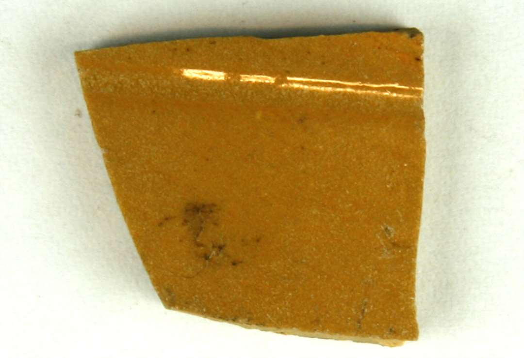 1 sideskår af gulligt finmagret, porøst lergods med klar glasur på yder- og indersiden, gruppe 1.