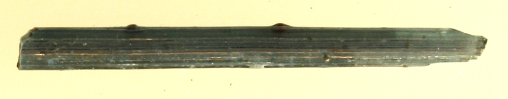En stump tråd af blåt glas. Længde: 2,5 cm.