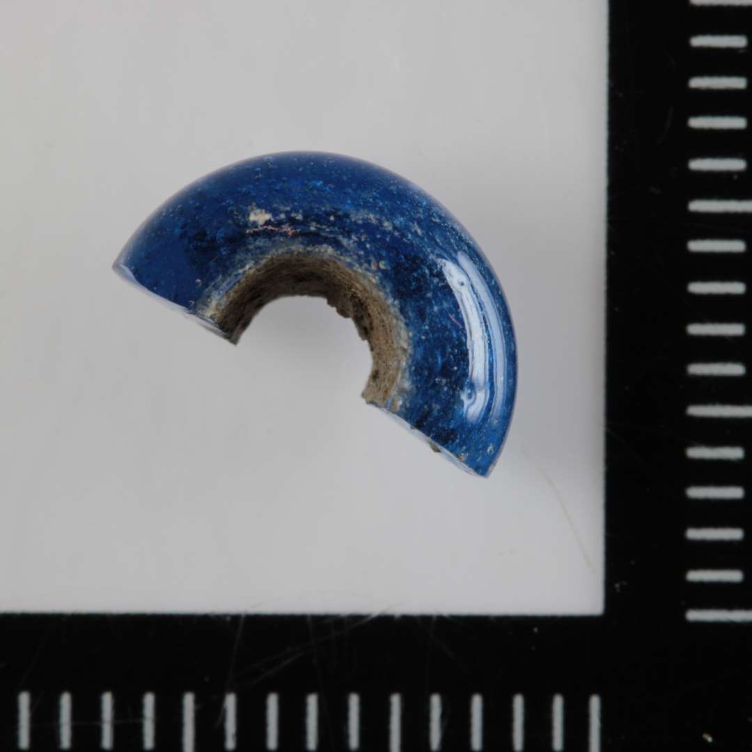 ½ ringformet perle af blåligt, gennemsigtigt glas. Diameter: 1,0 cm. tykkelse: 0,5 cm.