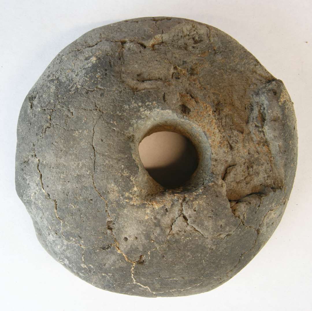 1 omtrent hel discosformet vævevægt af gråbrunlig brændt lermasse med lidt skævt placeret ophængningshul. Den ene side, er delvis plan, den anden hvælvet og noget fragmenteret. Diameter: 12,1 - 12,4 cm. Tykkelse:    4,7 cm.