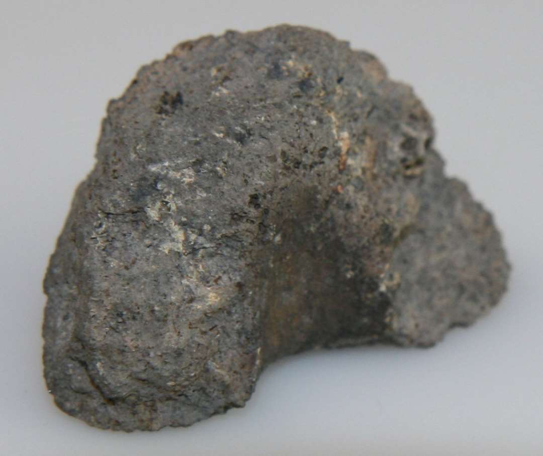 1 fragment af tøndeformet (?) tenvægt af gråbrændt lermasse.  Største bevarede mål: 3,7 cm. 2,5 cm.