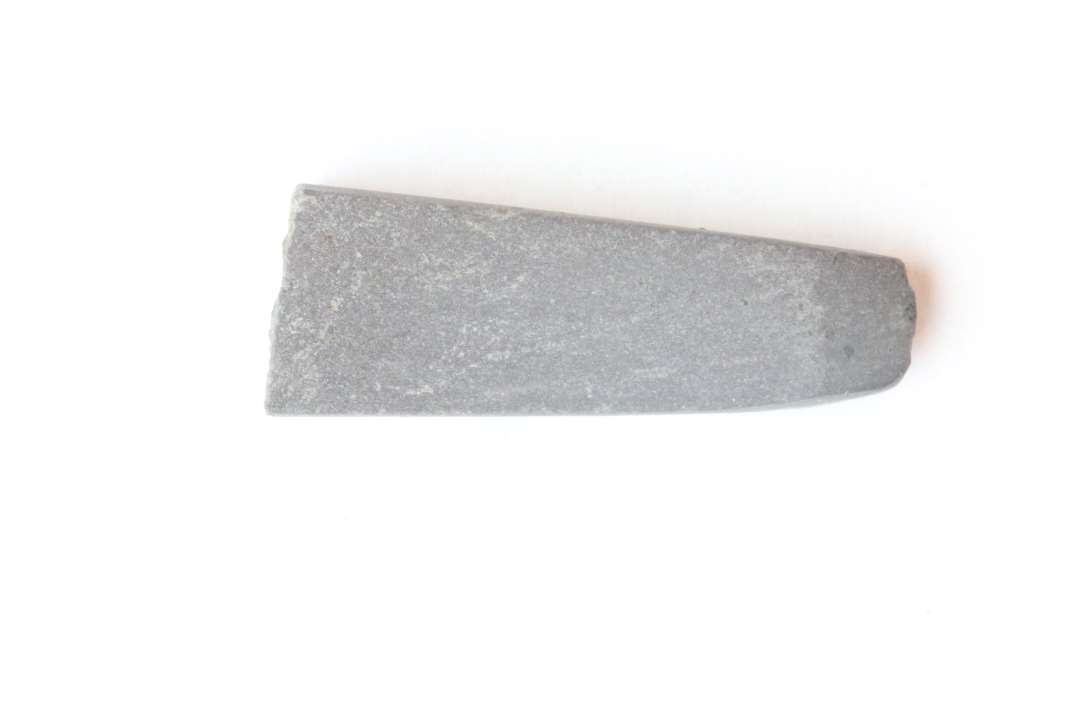 1 fragment af hvæssesten af dyblilla glatslebet skifer. Stykket har rektangulær tværsnitsform med tilspisning mod den bevarede ende. Længde:  2,5 cm. Tværmål: 0,9 x 0,5 cm.
