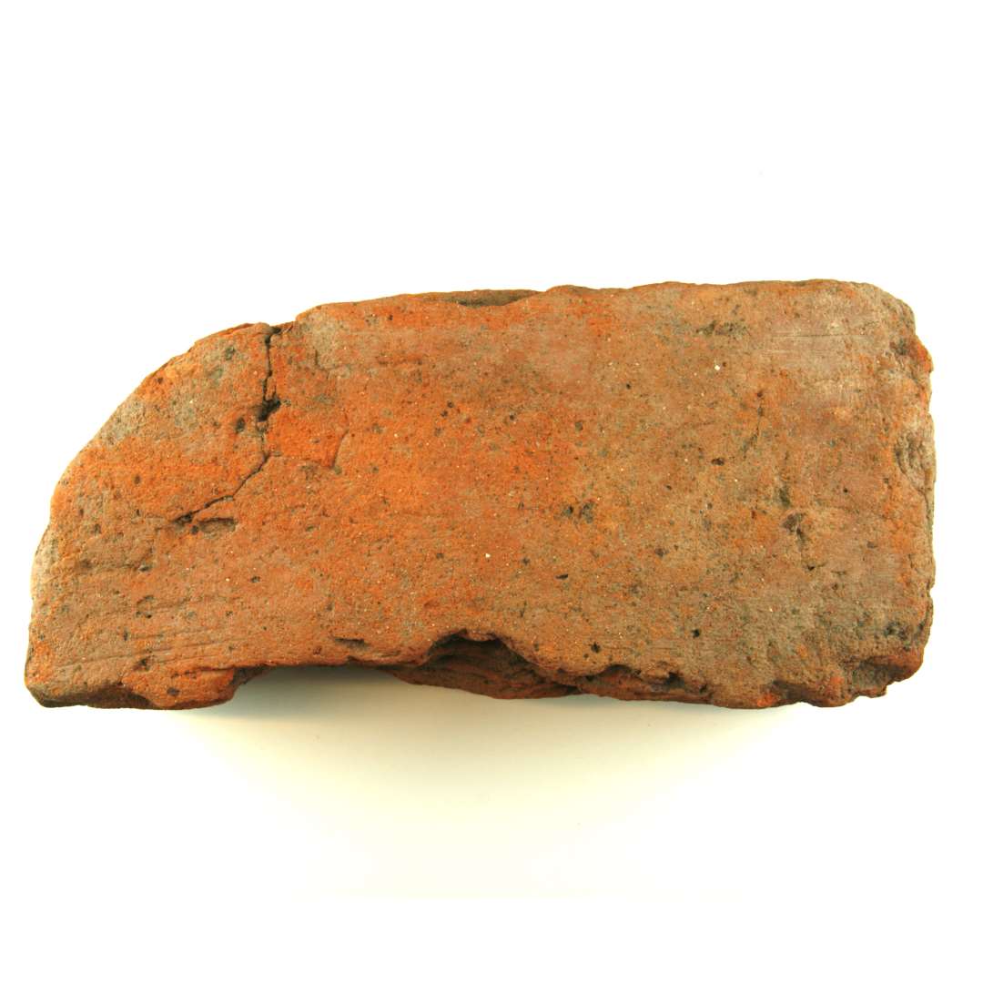 Teglsten af rødbrændt ler. Afrundet i den ene ende (sekundært). Højde: 8,5 cm. Bredde: 13,0 cm. Længde: 28,5 cm.