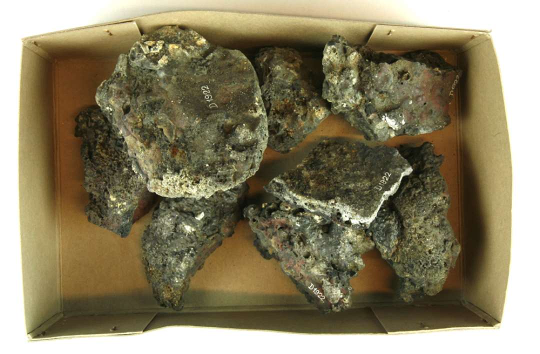9 jernslaggeklumper fra udsmeltning af myremalm. Slaggerne varierer i format fra knytnæve- til hønseægstørrelse, ligesom nogle har flad, udflydende, pandekageagtig form.