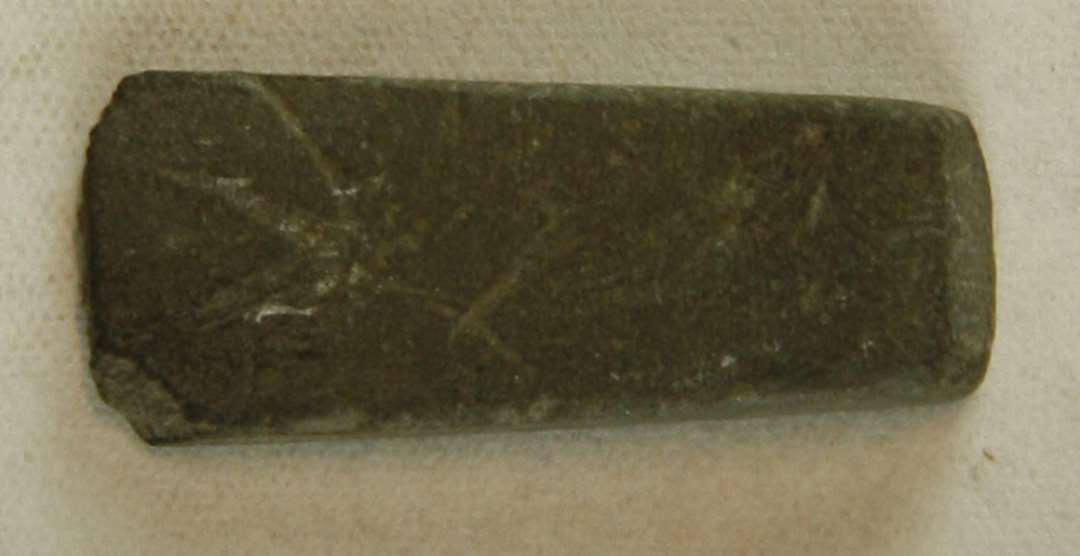 Fragment af violet hvæssesten, 2,5 cm x 1,0 cm.