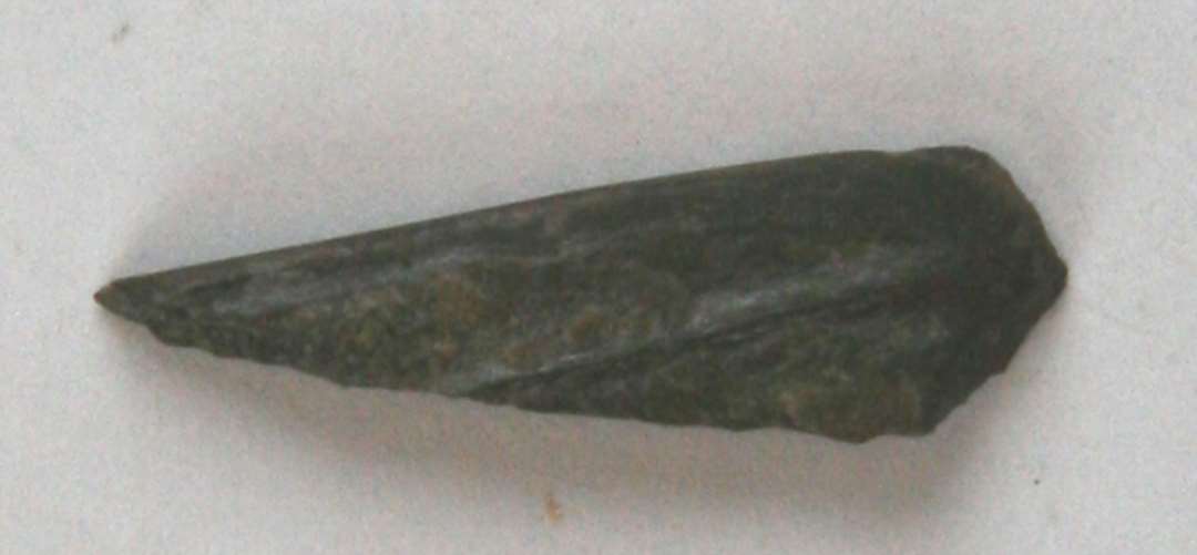 1 lille fragment af violet hvæssesten. Længde: 2,5 cm.