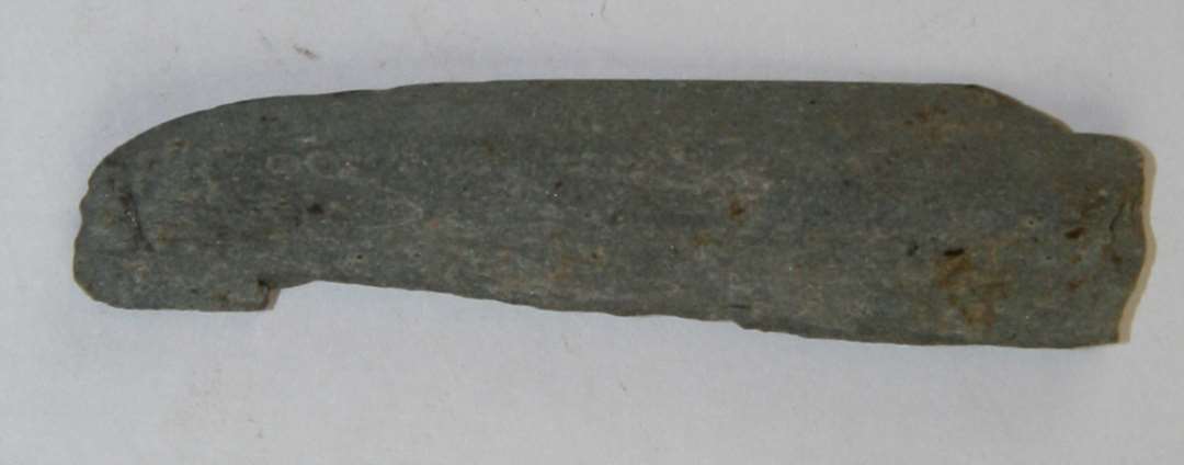 Hvæssesten af lys-grå skifer. Mindre fragment, ca. 5,5x1x0,5 cm  