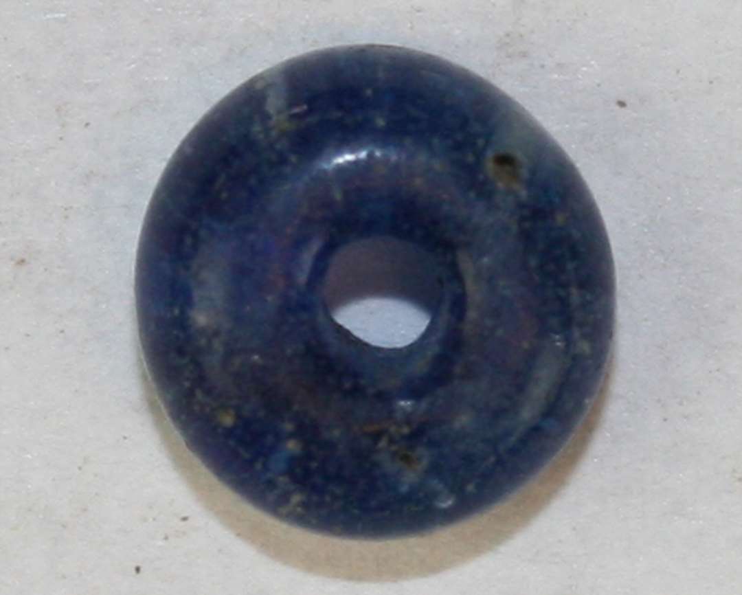 Hel, afskåret, ringformet, gennemsigtig blå perle. Diameter: 6 mm.