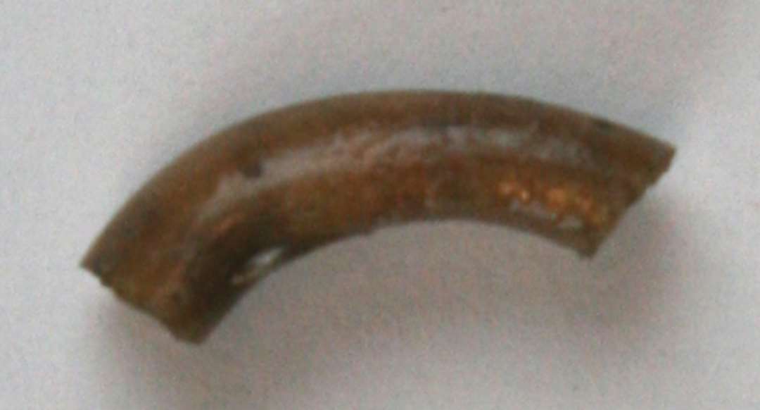 Fragment af glasring af uigennemsigtigt brunt glas. Mål: 1,8 cm.