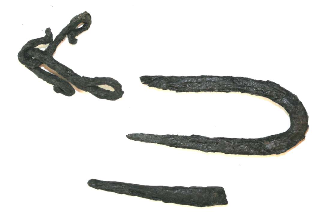 Tre genstande af jern. En del af kæde, to led bevaret, største mål: ca 2,8 cm., Krampe. Største mål: 4,5 cm., Spids fra søm eller lign., længde: 3,5 cm.
