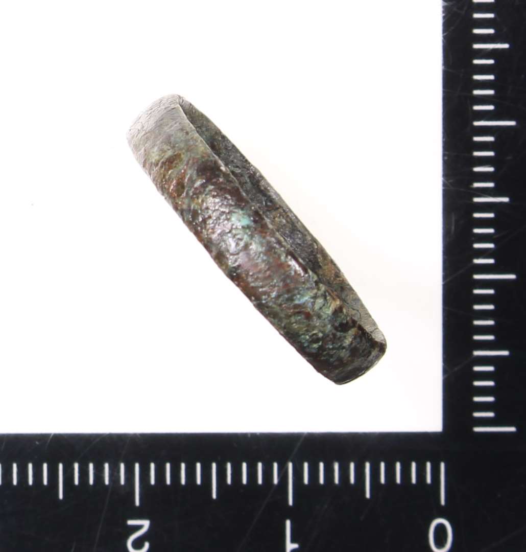 En fingerring af stærkt korroderet metal. Mål: 2,5 cm. i diameter.