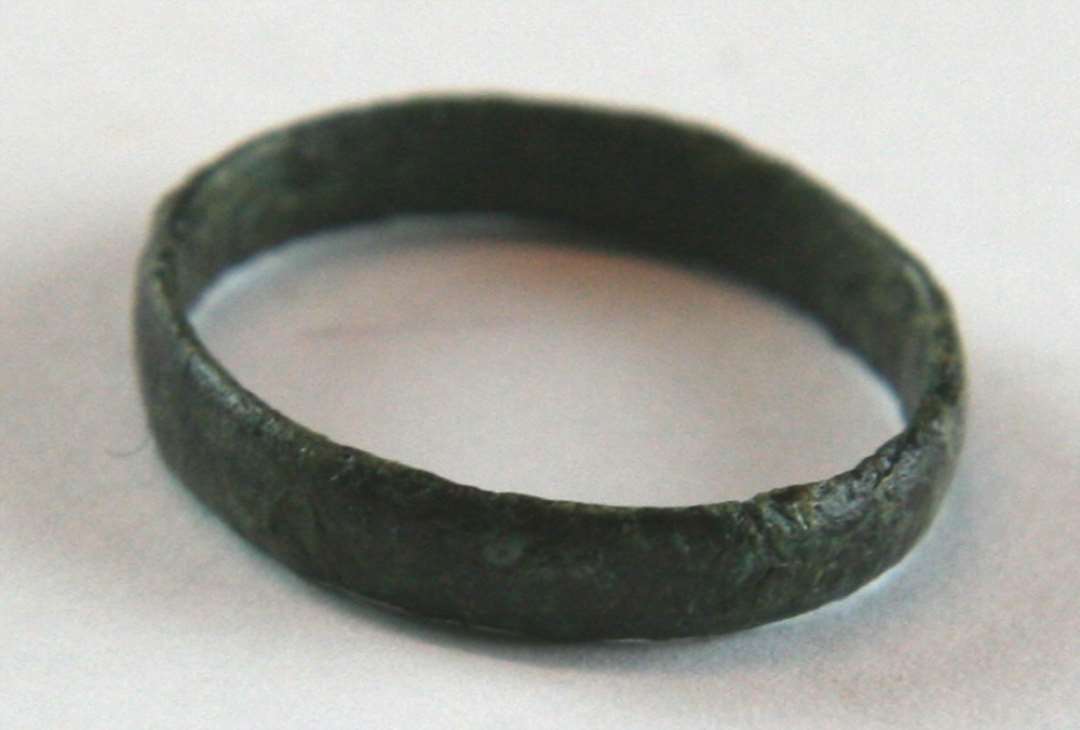 En fingerring af stærkt korroderet metal. Mål: 2,5 cm. i diameter.