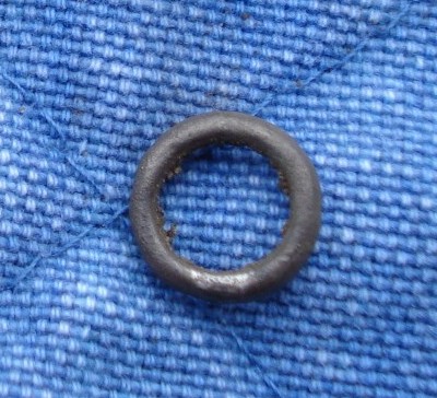 Ring af sølv. Cirkulært tværsnit, tråden 1½-2 mm. Ringens ydre diameter: 11mm. Spor efter sammenlodning. Alder og funktion? Snøremalle?