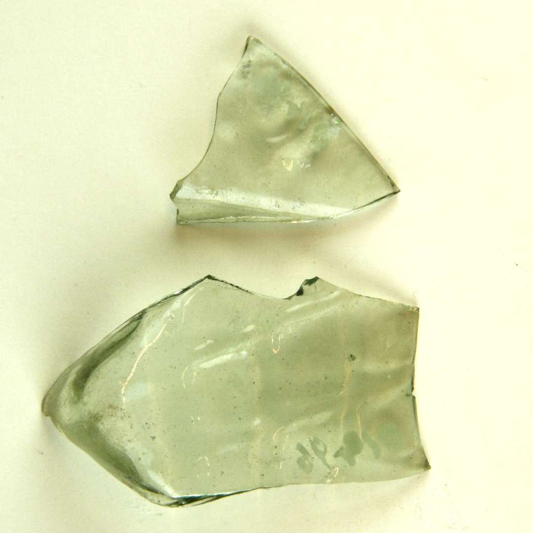 2 side- eller bundskår af flaske (?) lysgrønligt glas med 'vaflet' relief mønster. Mål: 5 x 3 og 3 x 2,5 cm.