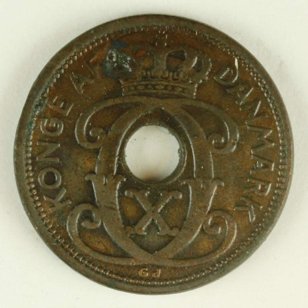 Kobbermønt, på den ene side C X under krone og 'KONGE AF DANMARK' og på den anden side 'DANMARK/ 1928/ 1 ØRE'. Hul i midten