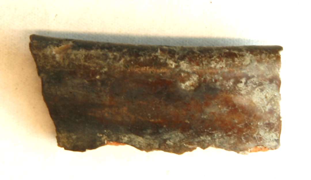1 randskår af rødbrændt magret lergods fra kar med glat afrundet læberand, der ligesom ydersiden er dækket af klar blyglasur.