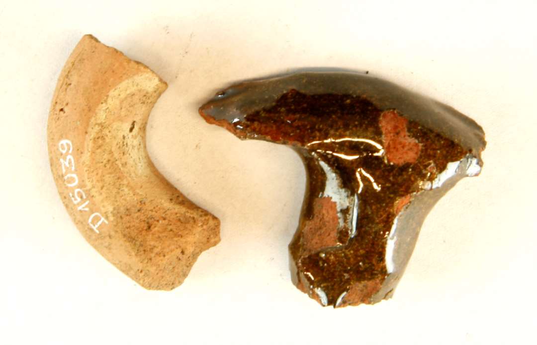 1 fragment af rødbrændt hank eller øre ? dækket af klar blyglasur, samt 1 do. med pletter af begitning og blyglasur.