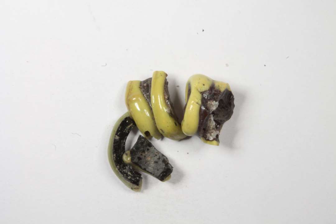 Fire fragmenter af cylindriske hvepseperler, uigennemsigtige sorte med gule bånd