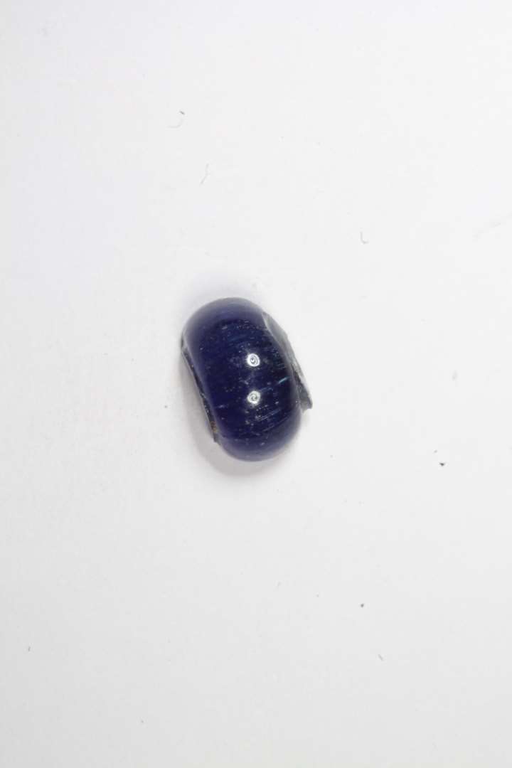 Halv ringformet, gennemsigtig blå glasperle. diameter: 0,8 cm.
