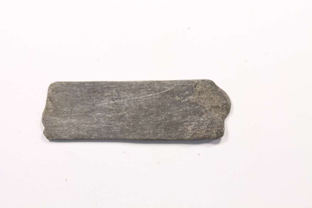  fragment af hvæssesten. Mørk skifer. Mål: 1,4x0,2x4,5 cm.