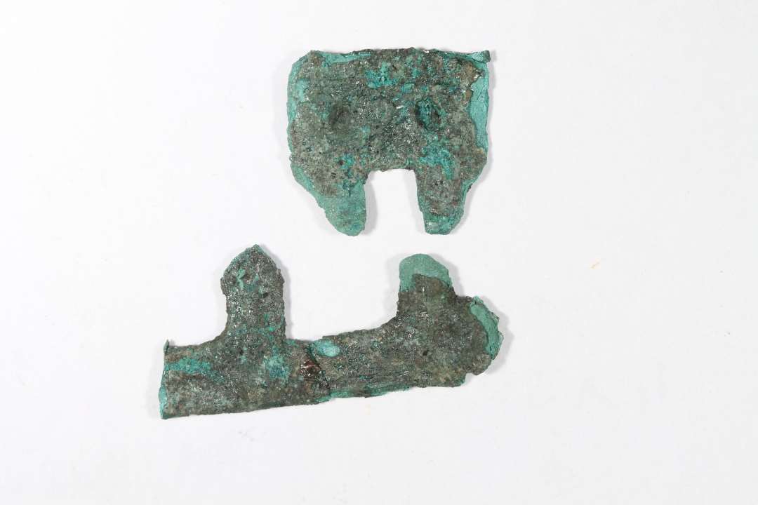 Gennembrudt, fragmenteret bronzebeslag. I to dele. Mål: 1,5 og 2,6 cm.