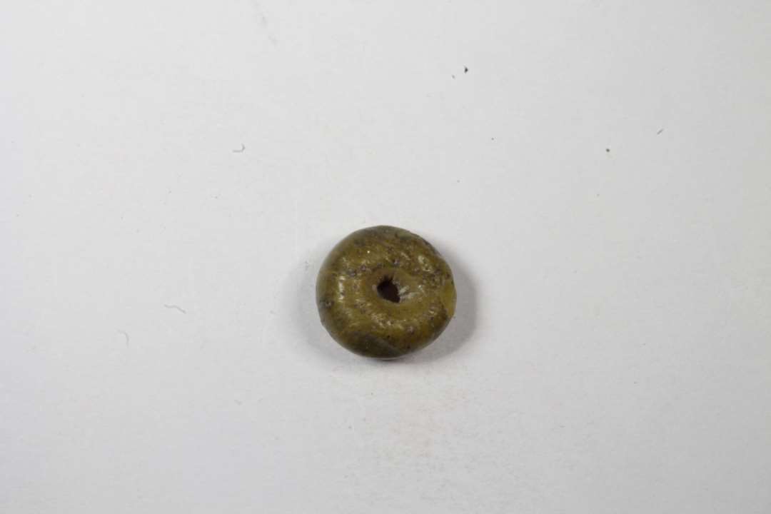 Cylindrisk afskåren, uigennemsigtig grumsetgul glasperle. Diameter: 0,6 cm.