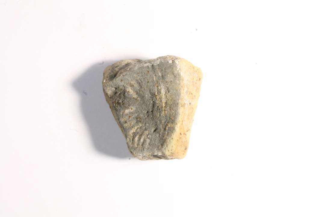 Fragment af støbeform til skålformet spænde. P13B. Styrefacet. Grå. Største mål: 2,4 cm.
