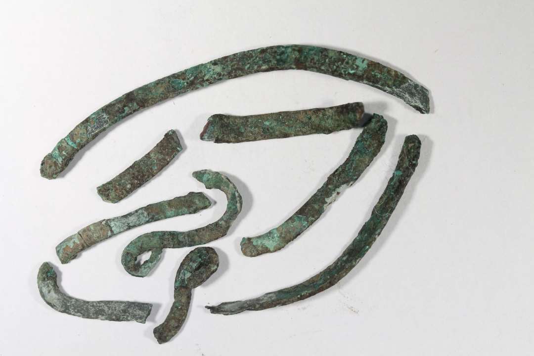 Stumper af smalle, lange blikbånd af bronze. enkelte vredet i S-form. Længde: 1,5-5,7 cm.