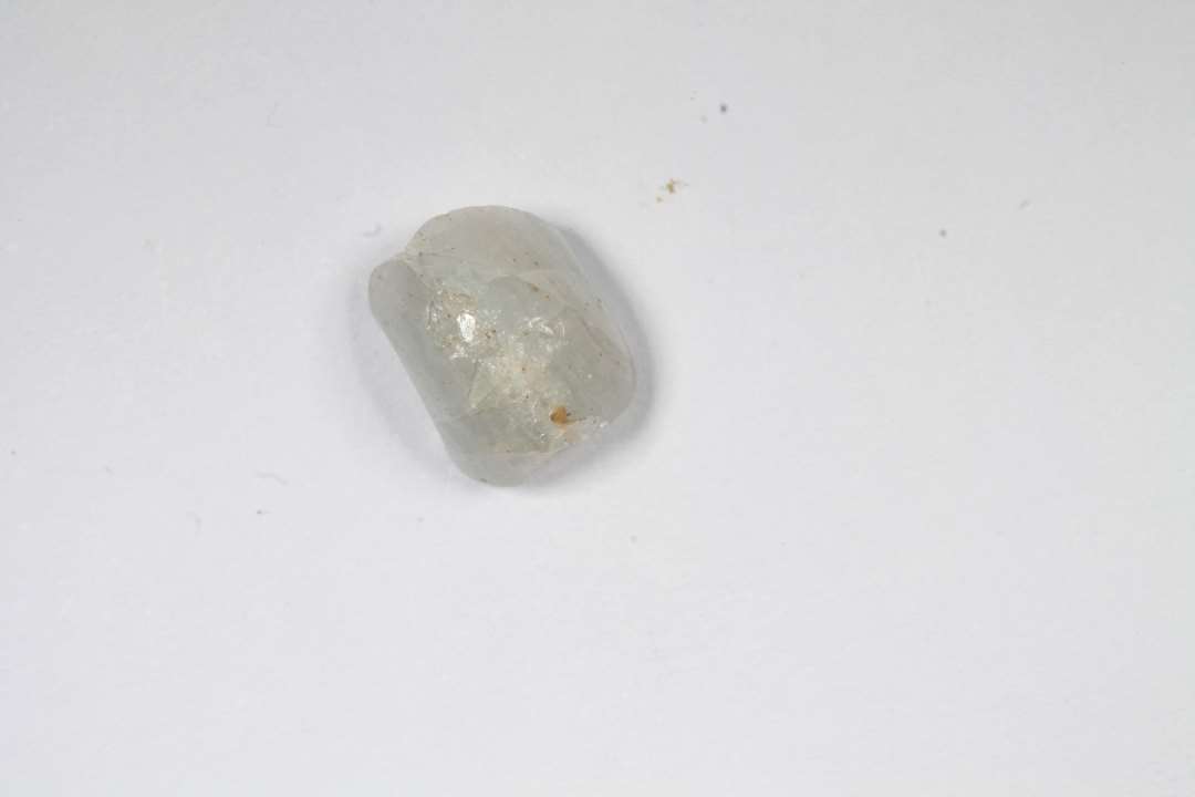 Fragment af ringformet, uigennemsigtig hvidgrå glasmasse. Diameter ca: 1 cm.