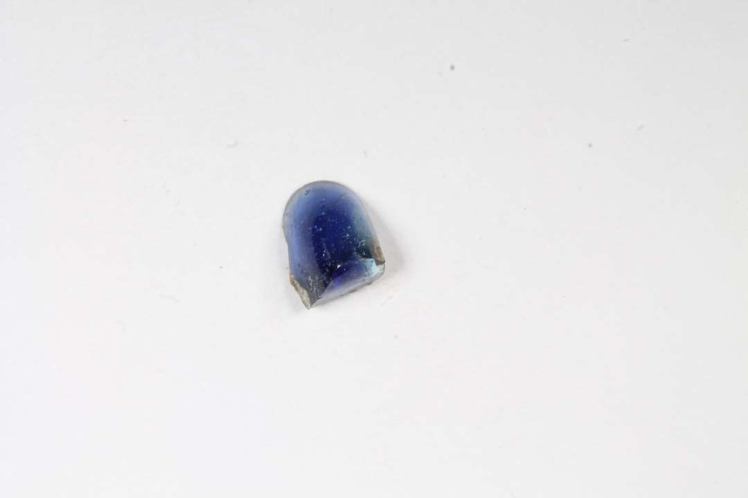 Fragment af ringformet, gennemsigtig blå glasperle. Mål: 0,3 cm.