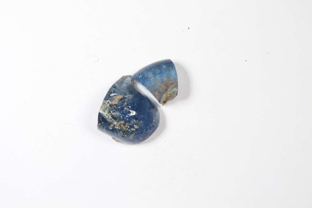 To fragmenter af ringformede, gennemsigtige, blå glasperler. Største mål: 0,5 og 0,7 cm.